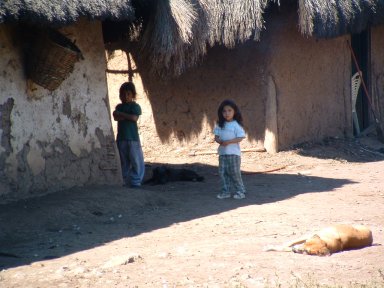 Curious girls in front of mud hut home